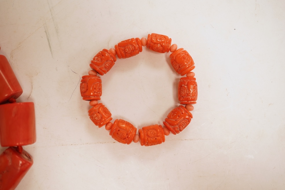 Two coral bead necklaces, one composed of large cylindrical coral beads, approximately 2.5-3.5cm each, total length 49cm; and a bracelet composed of carved coral beads spaced by smaller pink coral beads, on an elasticate